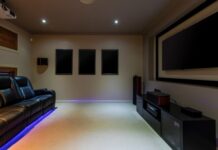 6 Tips for Turning a Backyard Shed Into a Home Theater A home theater room features a projector, a wall-mounted screen, and a black leather recliner sofa with LED floor lighting.
