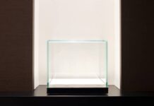 How To Create a Museum-Quality Display Case A well-lit but empty display case with a black bottom. The case is sitting in a white nook surrounded by dark walls.