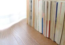 Long-Term Comic Book Storage Tips Every Collector Needs A line of books standing upright on a wooden surface. The pages are faced outward with the binding hidden.