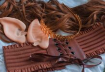 Tips To Take Your Cosplay to the Next Level A collection of items for an elf cosplay sit on a blue surface, including a wig, headband, corset, and ears.