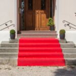 5 Fun Ways To Celebrate Movie Awards Nights With Friends A small red carpet sits on the steps of the front of a house. The carpet leads up to the front door.