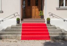 5 Fun Ways To Celebrate Movie Awards Nights With Friends A small red carpet sits on the steps of the front of a house. The carpet leads up to the front door.