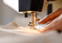 Understanding Thread Tension for Flawless Sewing Results A close-up view shows a person pushing white fabric through the sewing needle of a sewing machine.