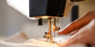 Understanding Thread Tension for Flawless Sewing Results A close-up view shows a person pushing white fabric through the sewing needle of a sewing machine.