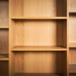 Level Up Your Lair: The Ultimate Geeky Collection Guide A light wood bookshelf with empty compartments, showcasing natural grain and warm tones, with shadows adding depth.