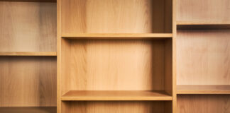Level Up Your Lair: The Ultimate Geeky Collection Guide A light wood bookshelf with empty compartments, showcasing natural grain and warm tones, with shadows adding depth.