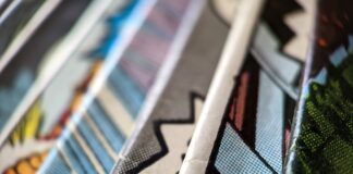 How to Protect Your Artwork And Comics at Home A closeup of a collection of comic books all stacked next to each other, with colorful, textured papers.